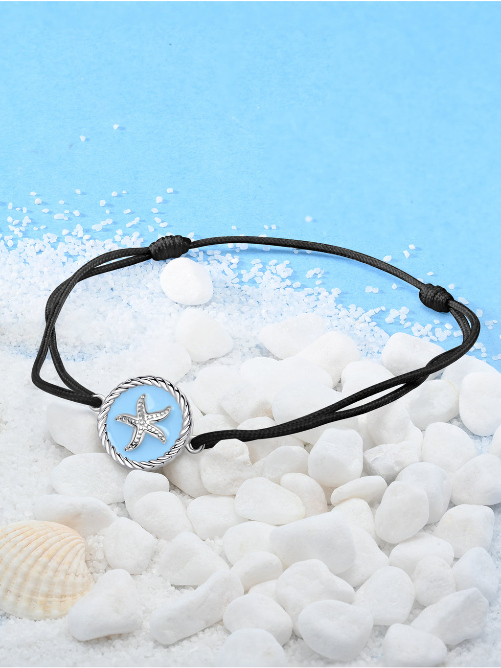 JENDEAR black string starfish anklet on white pebbles with seashell, blue sky background